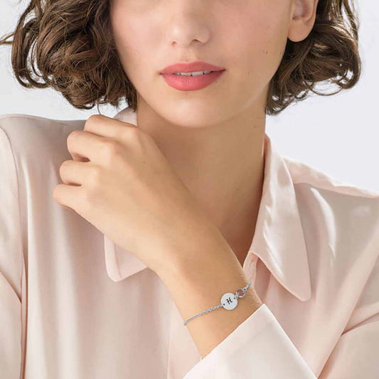 Woman wearing silver personalized initial disc bracelet with birthstone, engraved letter.