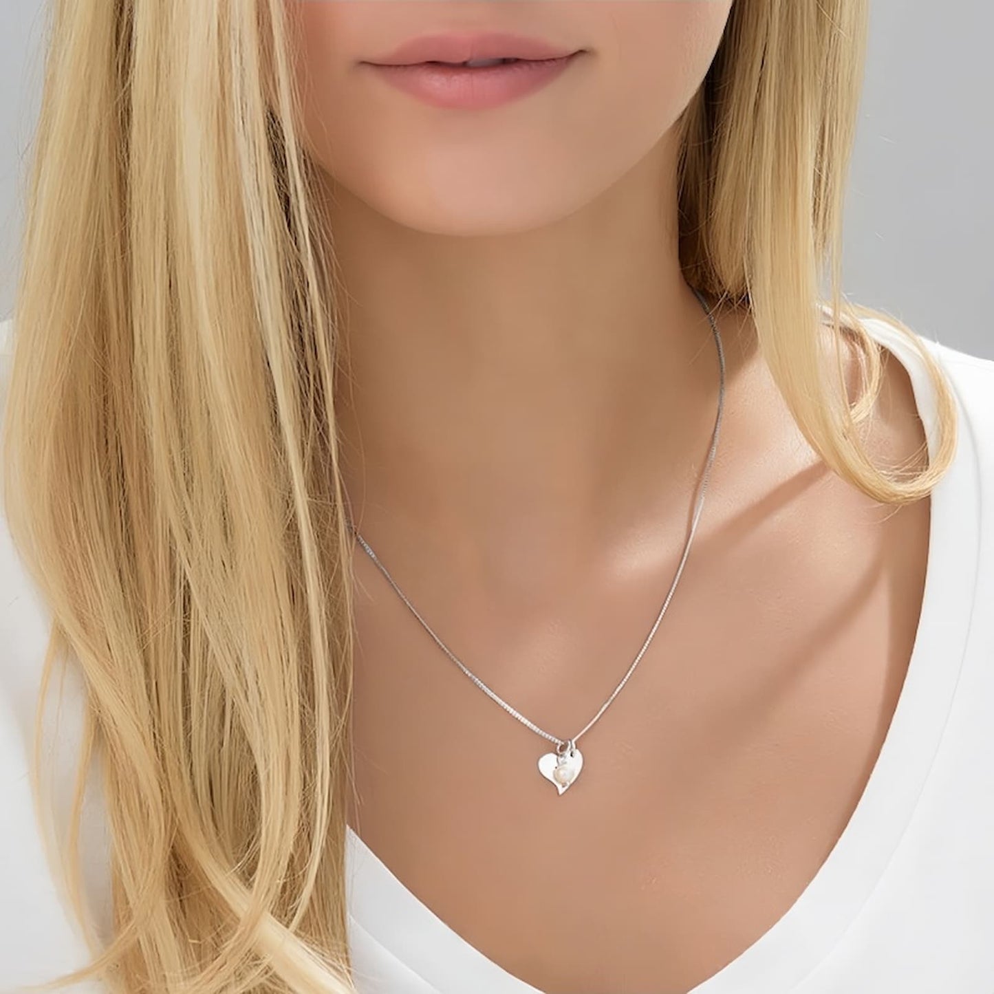 Close-up of a woman wearing a personalized 925 sterling silver heart initial necklace with a pearl.