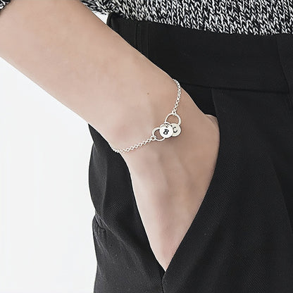 Women's wrist wearing custom 925 silver infinity initial charm bracelet.